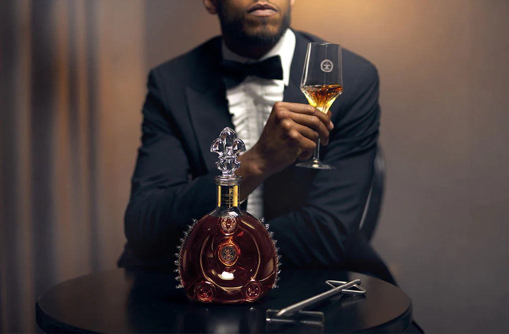 A photo of a man touching LOUIS XIII bottle, a bar in the background