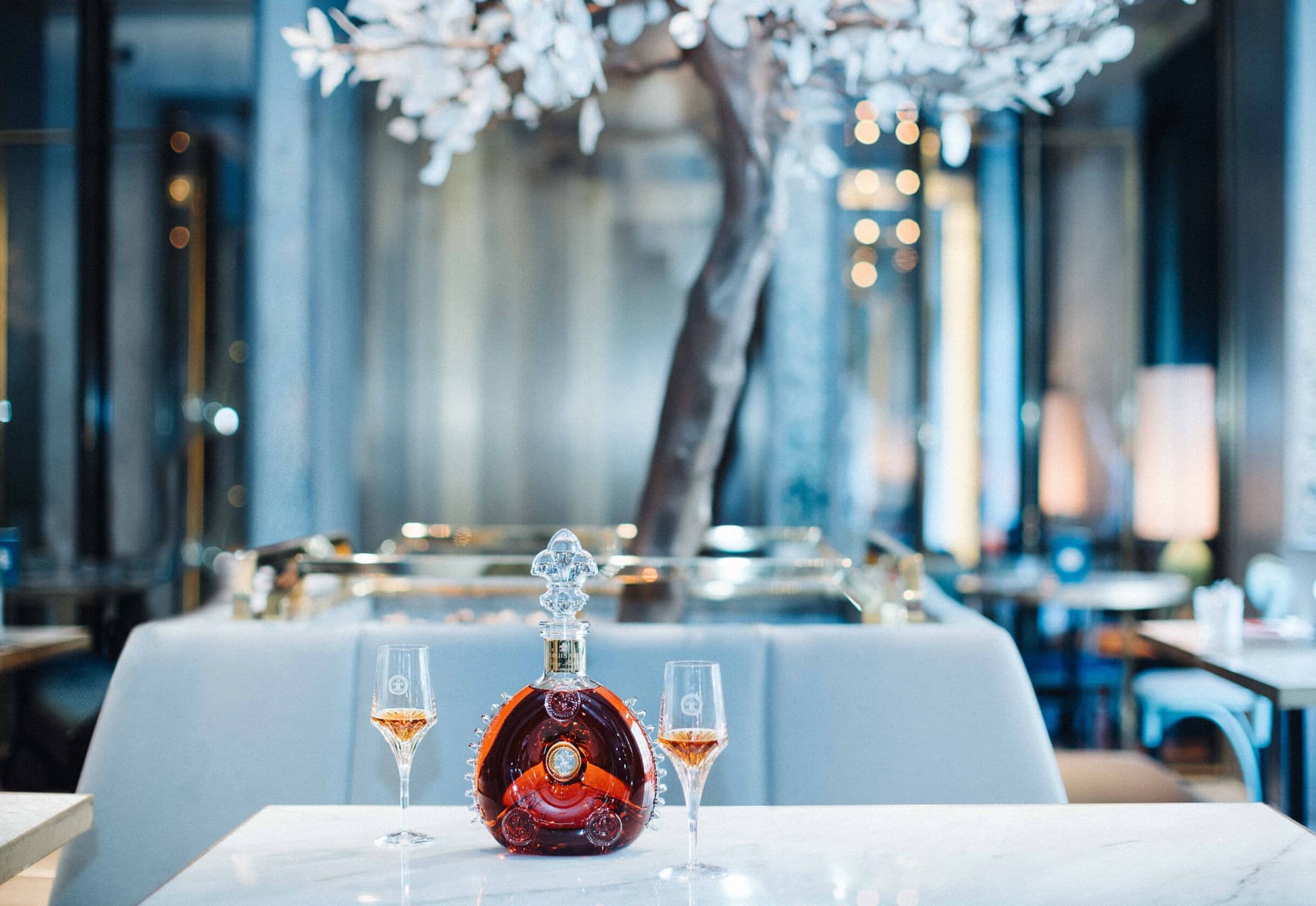 A photo of a LOUIS XIII decanter with two glasses on a restaurant table