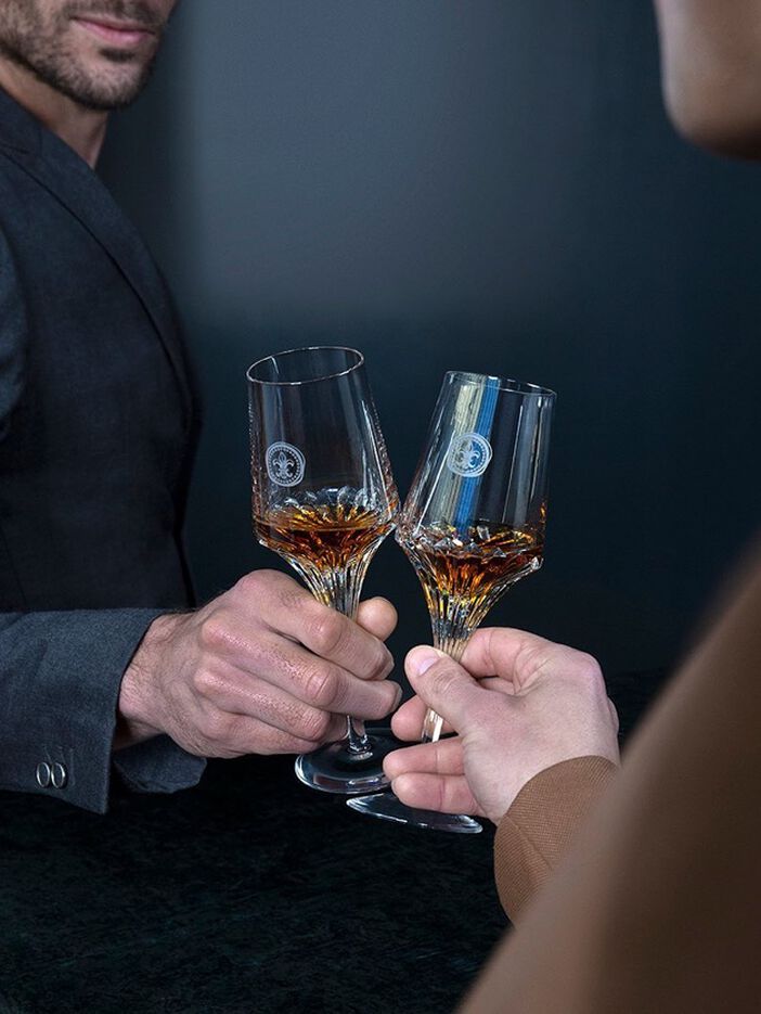 A lifestyle picture of two people toasting with crystal glasses