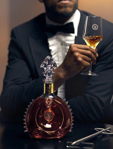 An image of a man watching a bartender serving LOUIS XIII cognac with a spear
