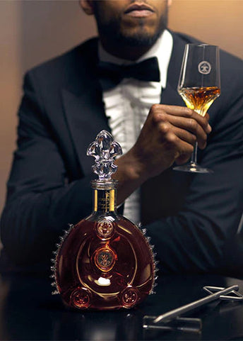 An image of a man watching a bartender serving LOUIS XIII cognac with a spear