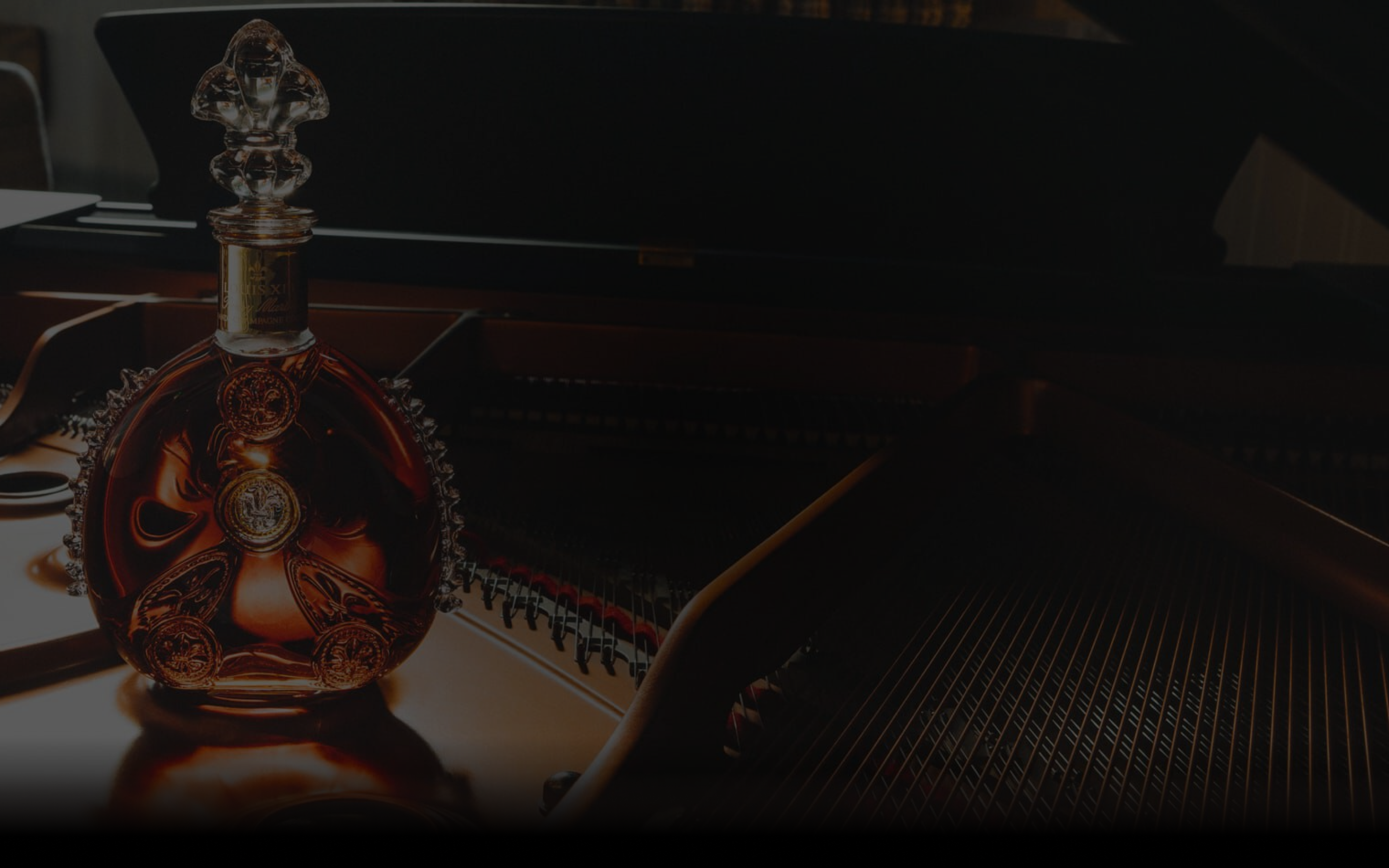 A dimmed image of LOUIS XIII decanter standing on an open piano