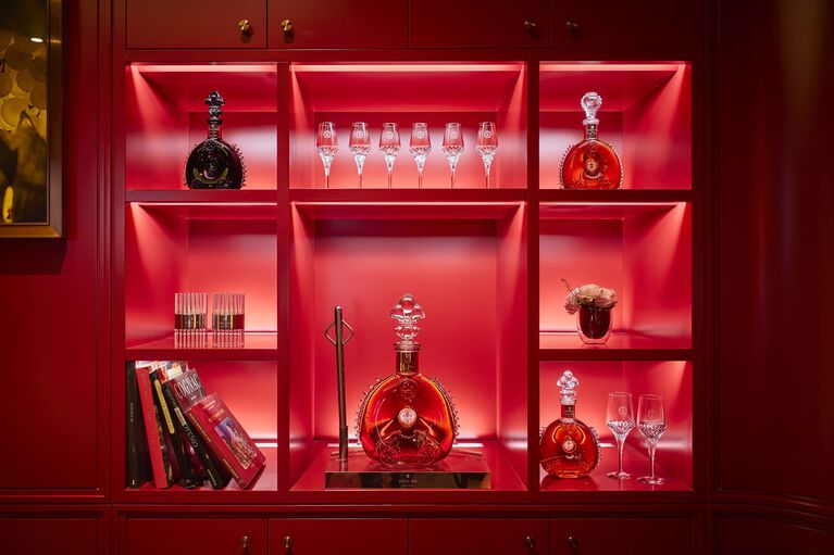 A lifestyle photo of few LOUIS XIII decanters in a red vitrine