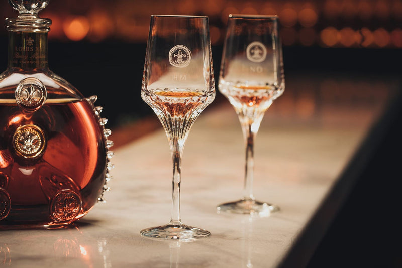 A lifstyle photo of two crystal glasses and a decanter on a bar countertop