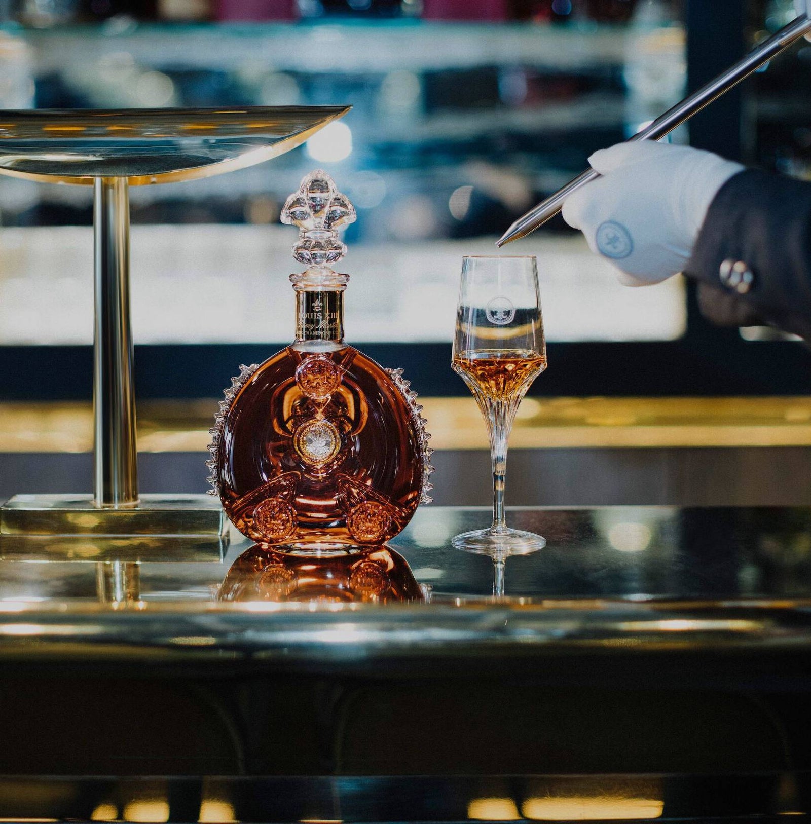 A lifestyle photo of a bartender serving LOUIS XIII with a spear, a decanter close to a crystal glass