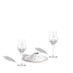 A packshot of two LOUIS XIII crystal glasses and a serving utensil for bellota ham